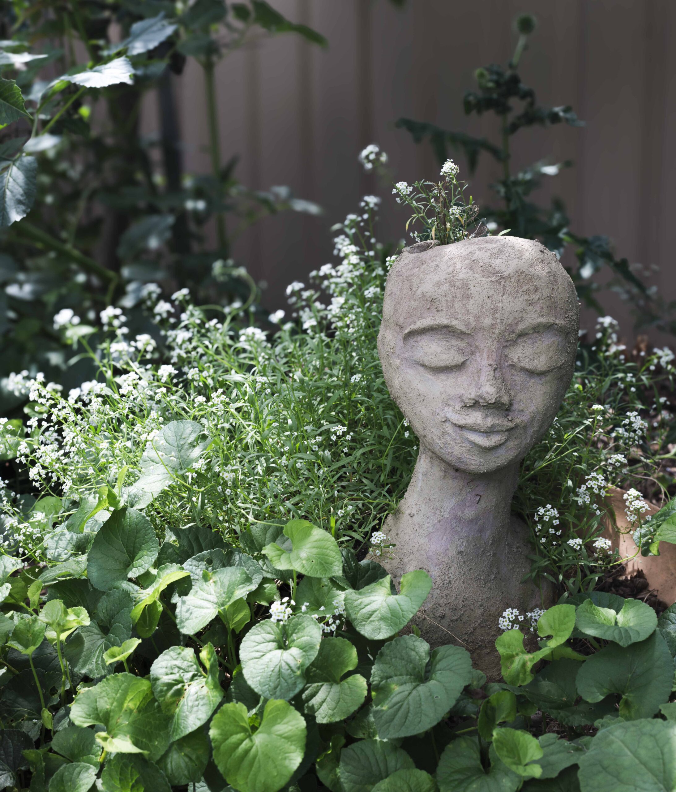 head sculpture in front of foliage