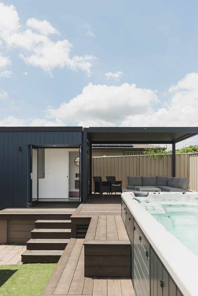 Backyard office and adjoining verandah from front with tiered decking  and spa in foreground
